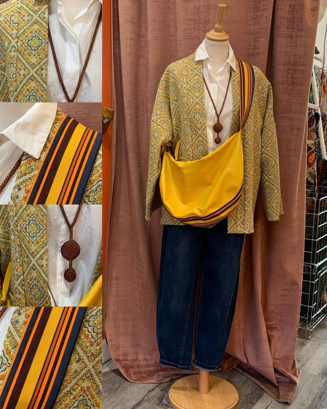 Photographie d'un mannequin en bois avec une tenue, jeans bleu, chemise blanche, veste jaune, collier en maille, sac encuir jaune